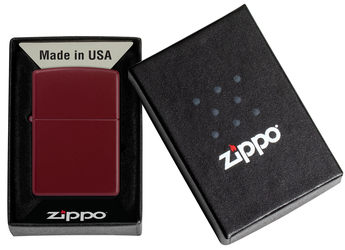 Ein weinrotes Zippo-Feuerzeug liegt in einer offenen schwarzen Schachtel mit der Aufschrift "Made in USA" und "Zippo".