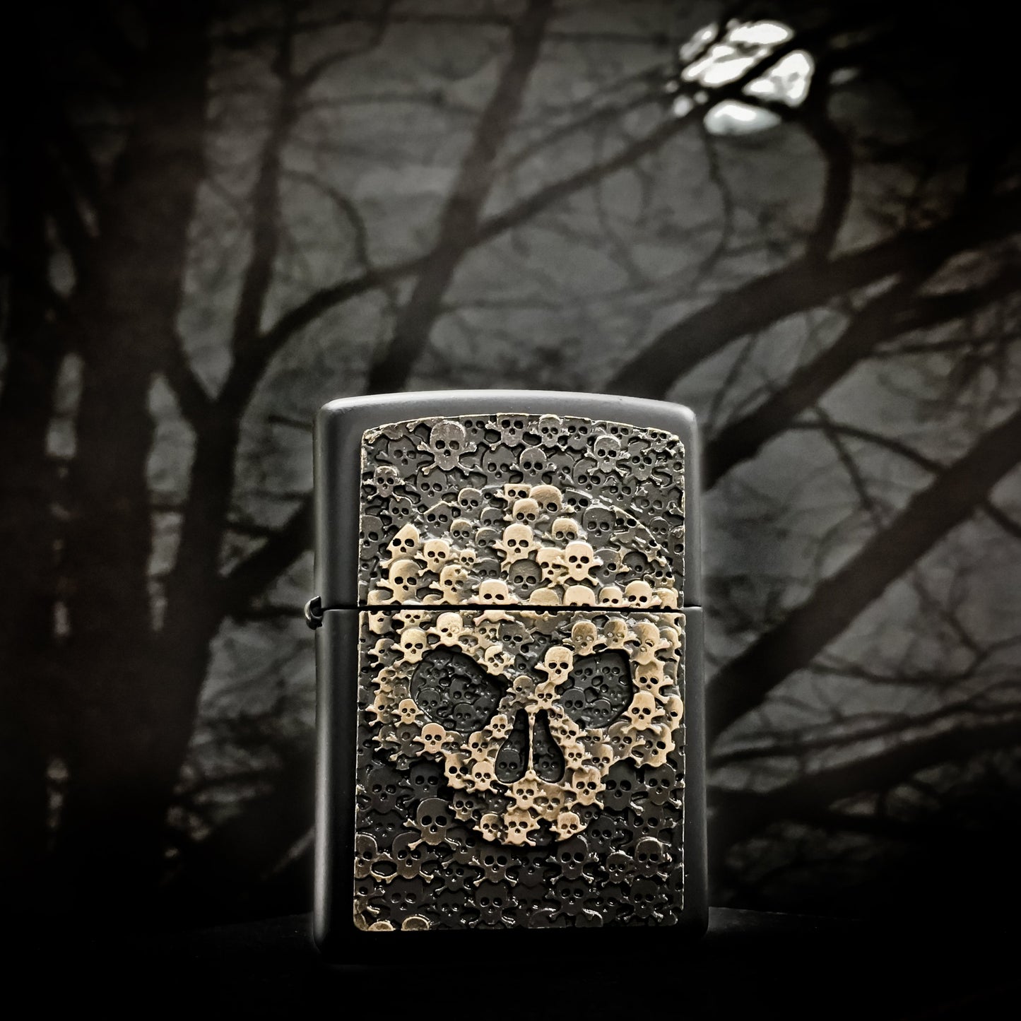 Frontansicht Zippo Feuerzeug schwarz Totenkopf bestehend aus vielen kleinen Totenköpfen Emblem mit illustriertem Hintergrund