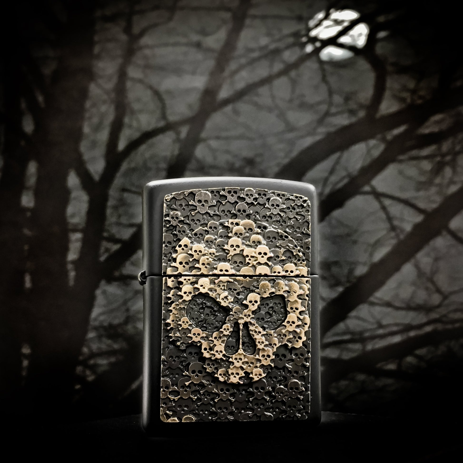 Frontansicht Zippo Feuerzeug schwarz Totenkopf bestehend aus vielen kleinen Totenköpfen Emblem mit illustriertem Hintergrund